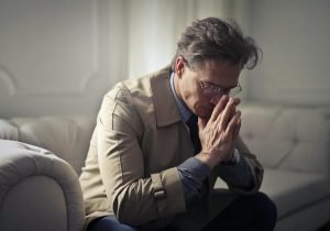 man sat on sofa with hands on mouth